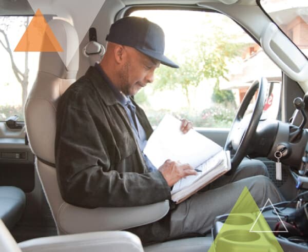 A man sits behind the wheel of his vehicle looking through the trip manifest. MTM Transit offers our clients with paratransit fleets our ADA paratransit brokerage approach and brokerage model.