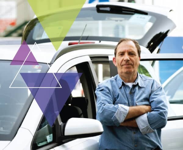 A man stands in front of his vehicle with his arms crossed. To increase the performance of paratransit fleets, MTM Transit utilizes the ADA paratransit brokerage approach and brokerage model.